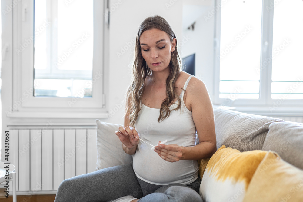 Pregnant woman taking a Self-swabbing home tests for COVID-19 at home with Antigen kit. Introducing nasal stick to check the infection of Coronavirus. Quarantine, pandemic. Pregnant woman taking a Self-swabbing home tests for COVID-19 at home with Antigen kit. Introducing nasal stick to check the infection of Coronavirus. Quarantine, pandemic.