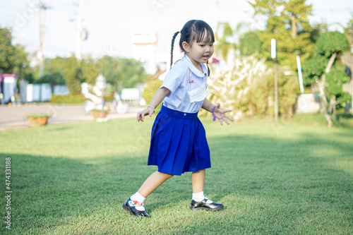 PHRAE, THAILAND – NOVEMBER 20: Asian girl in kindergarten uniforms relaxes outside the building on the December 20,2021 in PHRAE,TH.