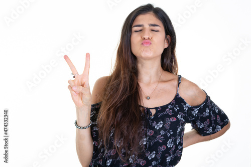 Young woman smiling happy face showing two fingers v positive and peace gesture on white background