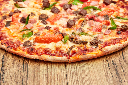 Italian pizza with meat, close-up on a wooden table top