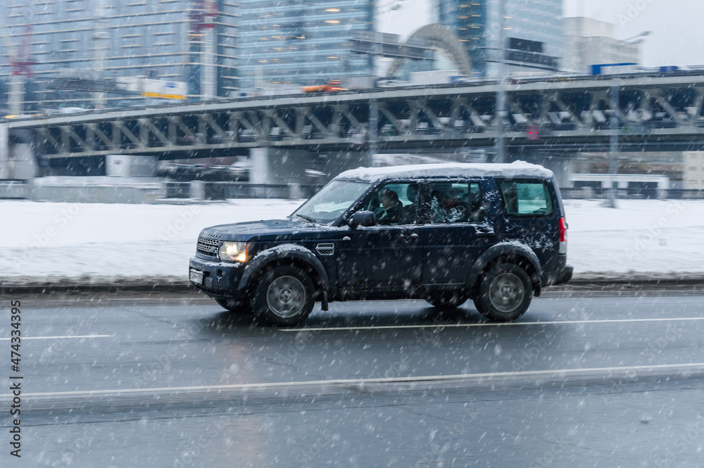 Fast moving Land Rover Discovery 4 on winter city road. Black SUV with ...