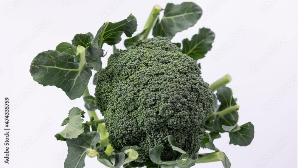 Organic broccoli spinning on white