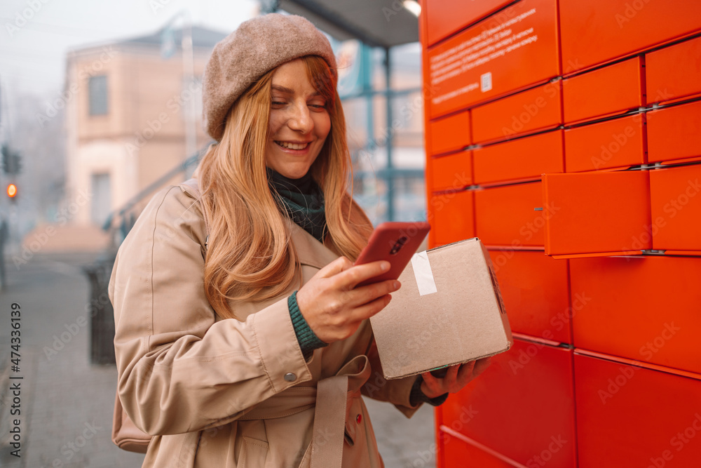 Young caucasian woman received parcel using automated self-service post terminal machine. Freight transportation. Express delivery. - obrazy, fototapety, plakaty 
