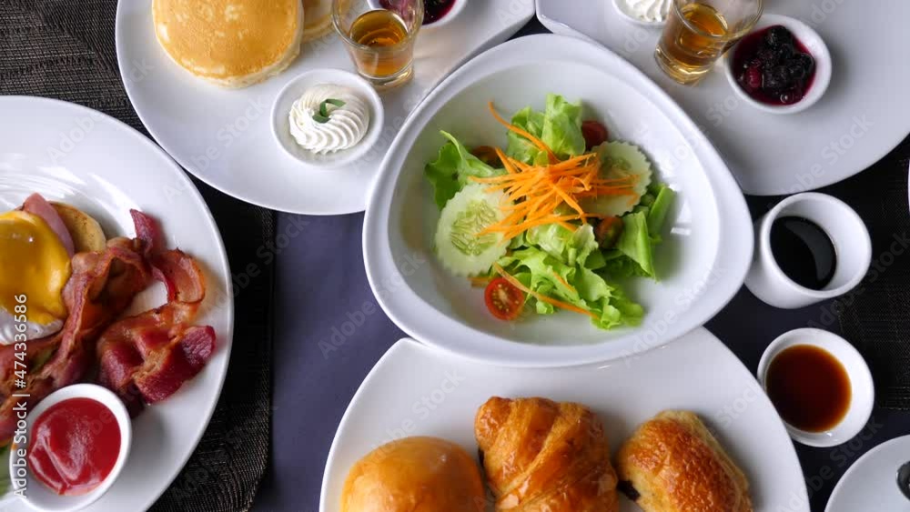 Hotel or resort buffet breakfast. Table with food, drinks for dinner, lunch, brunch in restaurant or cafe. Delicious meals, salad, fresh pastry, bakery, coffee cup, fried eggs. Slow motion. Top view. Hotel or resort buffet breakfast. Table with food, drinks for dinner, lunch, brunch in restaurant or cafe. Delicious meals, salad, fresh pastry, bakery, coffee cup, fried eggs. Slow motion. Top view.