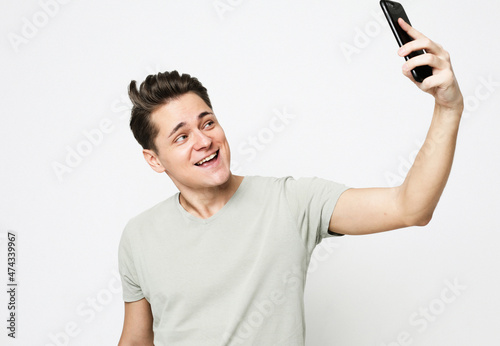 Portrait of friendly handsome caucasian man taking selfie or videocalling with mobile phone