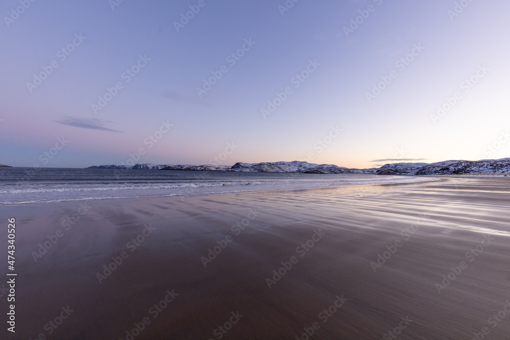 A huge and wide sandy beach of the Arctic Ocean at sunset. Teriberka village, Murmansk region, Russia.