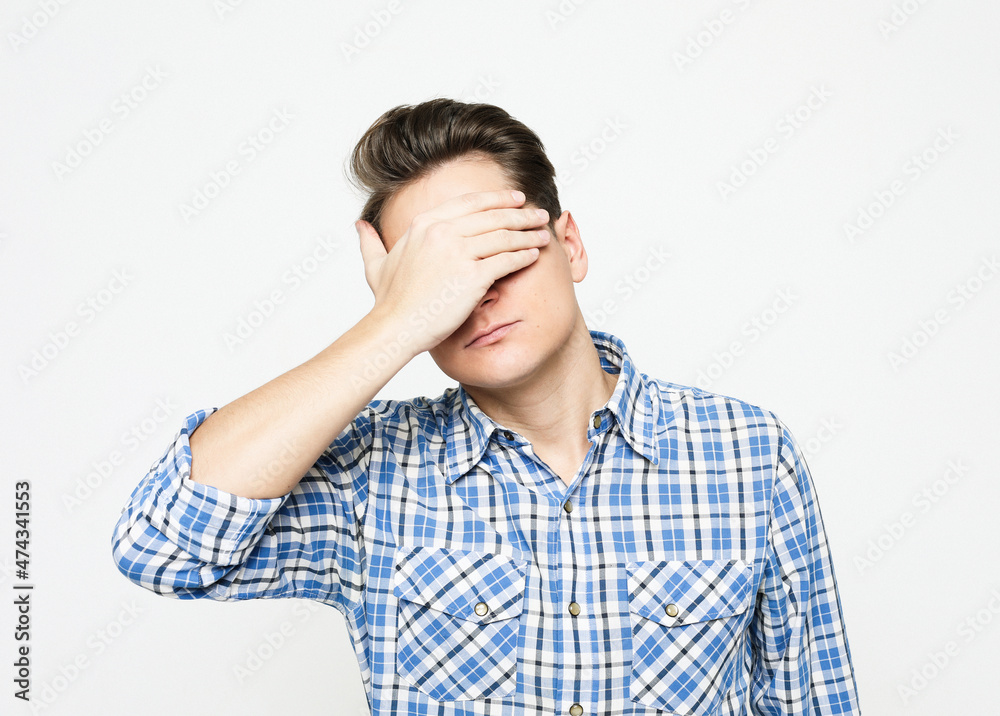 Young handsome man covering eyes with hands isolated over grey background Young handsome man covering eyes with hands isolated over grey background