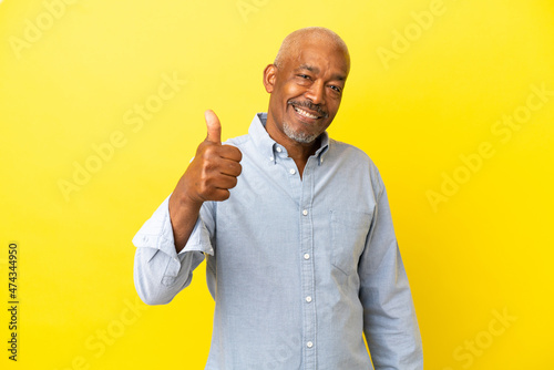 Cuban Senior isolated on yellow background giving a thumbs up gesture