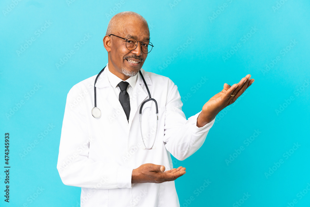 Senior doctor man isolated on blue background extending hands to the side for inviting to come Senior doctor man isolated on blue background extending hands to the side for inviting to come