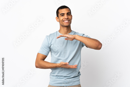African American man over isolated white background holding copyspace imaginary on the palm to insert an ad