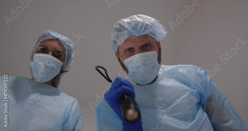 Doctor and nurse bent over the patient. He touch the pulse examines the patient, shines a flashlight in the eyes and checks reaction of pupils,  pronounced death and covered  face with a sheet.