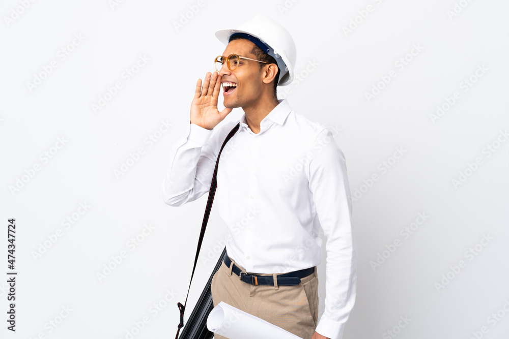 African American architect man with helmet and holding blueprints over isolated white background _ shouting with mouth wide open to the side African American architect man with helmet and holding blueprints over isolated white background _ shouting with mouth wide open to the side