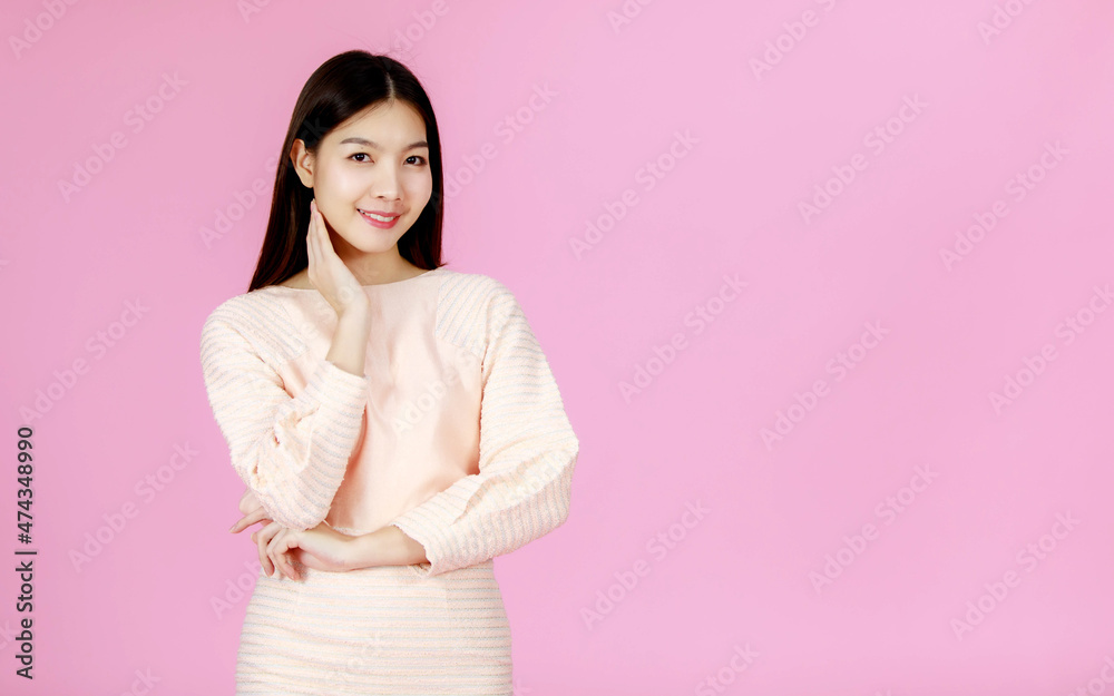 Portrait studio shot of Asian young happy beautiful pretty long black hair female teenager model in casual sweater outfit standing look at camera on pink background Portrait studio shot of Asian young happy beautiful pretty long black hair female teenager model in casual sweater outfit standing look at camera on pink background