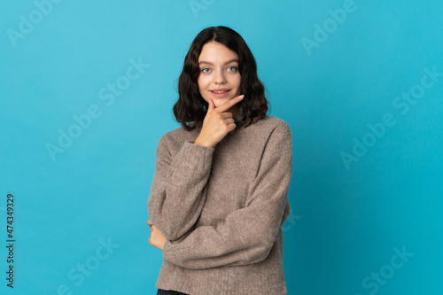 Teenager Ukrainian girl isolated on blue background happy and smiling