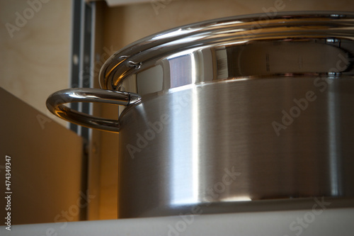Shiny stainless steel pan on a kitchen shelf