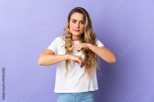 Young Brazilian woman isolated on purple background making the gesture of being late