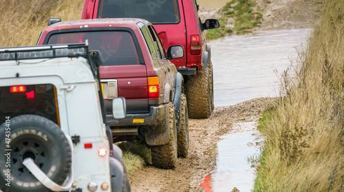 4x4 off-road vehicle driving across mud, water-logged terrain and wading through deep water pools, Wilts UK. Land Rover Discovery, Defender and Toyota 4Runner Hilux Surf © Martin