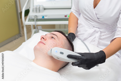 Man in a cosmetology office receives a SMAS lifting procedure. Non-surgical ultrasound facelift, rejuvenation, moisturizing, getting rid of wrinkles, skin tone and elasticity