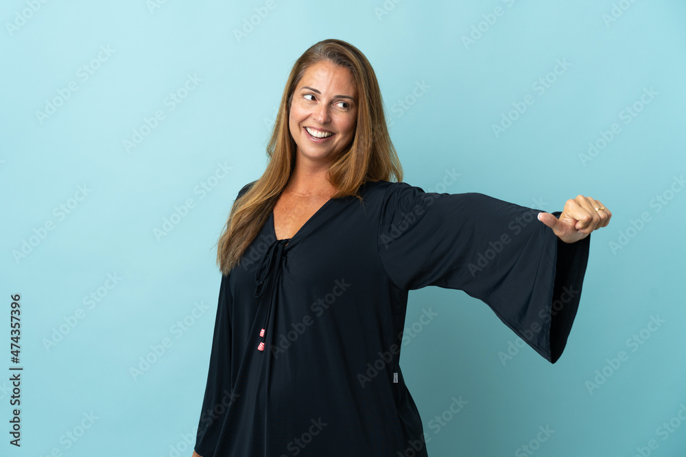 Fototapeta premium Middle age brazilian woman isolated on blue background giving a thumbs up gesture