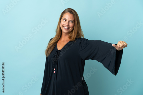 Middle age brazilian woman isolated on blue background giving a thumbs up gesture © luismolinero