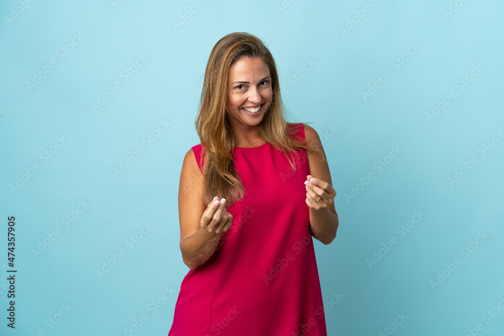 Middle age brazilian woman isolated on blue background making money gesture Middle age brazilian woman isolated on blue background making money gesture