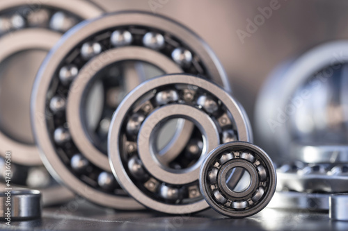 The concept of spare parts for mechanical engineering and modification of large heavy equipment in the form of ball bearings of different sizes, displayed in a row close-up. Steel bearings.