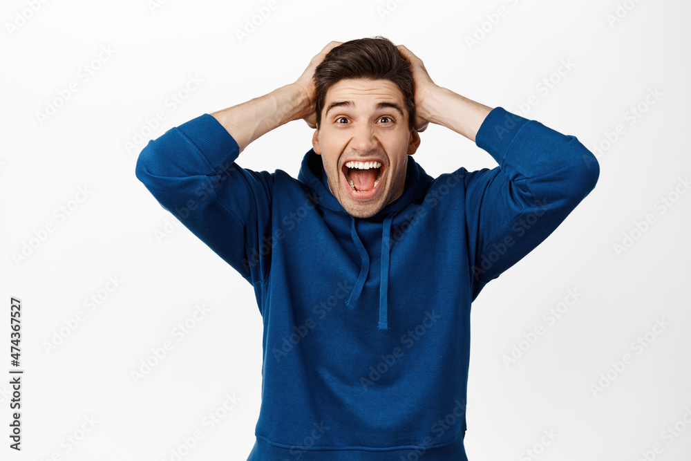 Image of excited brunette guy shouting of joy and surprised, winning prize, looking with disbelief and happiness at camera, triumphing over achievement, white background Image of excited brunette guy shouting of joy and surprised, winning prize, looking with disbelief and happiness at camera, triumphing over achievement, white background