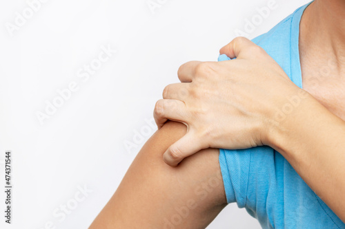 Cropped shot of a young woman in a blue t-shirt holding a shoulder in her hand isolated on a white background. Shoulder injuries  arm pain  neuralgia. Close-up