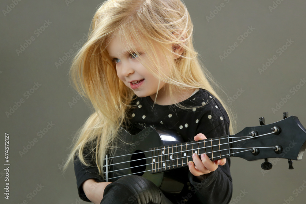 Studio portrait of adorable little girl playing ukulele	