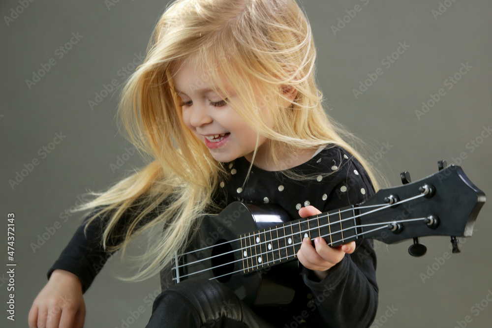 Studio portrait of adorable little girl playing ukulele	