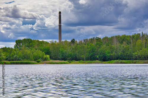 Wasser des Kulkwitzer See mit Schornstein im Hintergrund, Leipzig in Sachsen, Wasser, Baum, Herbst, Sommer photo