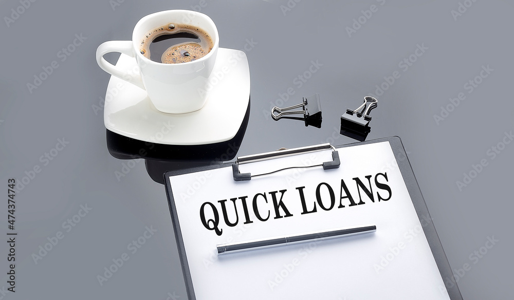 QUICK LOANS text on paper sheet with coffee on the black background QUICK LOANS text on paper sheet with coffee on the black background