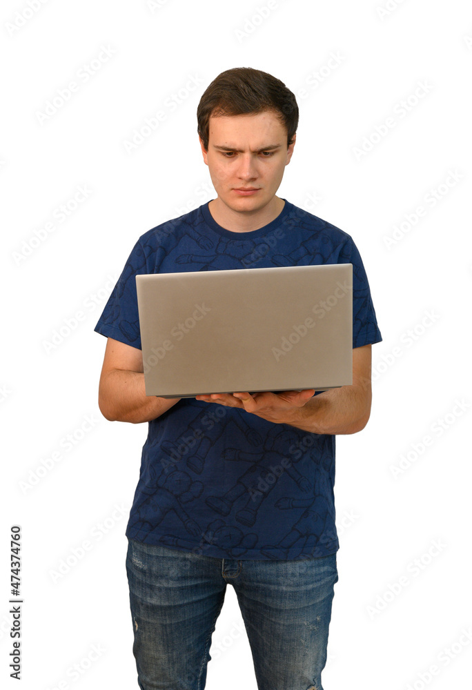 A young attractive man holds a laptop in one hand and looks at the screen with a pensive look A young attractive man holds a laptop in one hand and looks at the screen with a pensive look