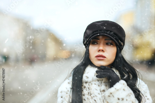 Stunning lady walking at the winter city during snowfall