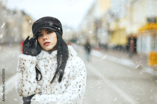 Fabulous lady walking at the winter city during snowfall