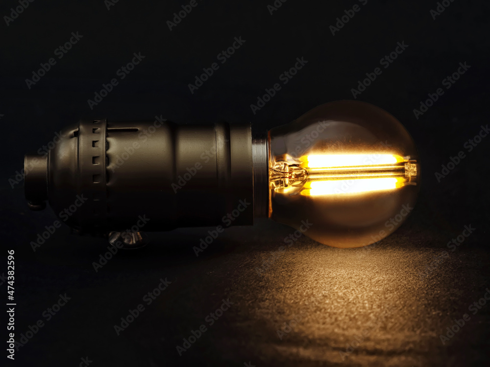 Matte spherical LED filament light bulb on the background of dark background. Close-up Matte spherical LED filament light bulb on the background of dark background. Close-up