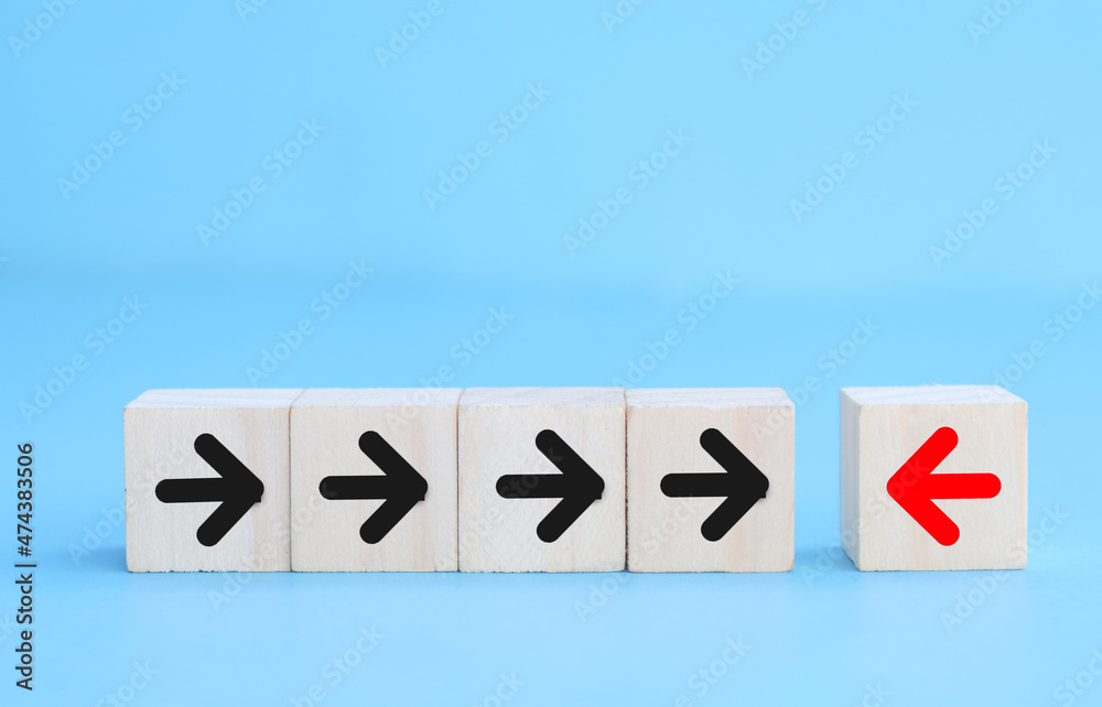 A wooden cube with an arrow pointing in a different direction from the other wooden cubes. A wooden cube with an arrow pointing in a different direction from the other wooden cubes.