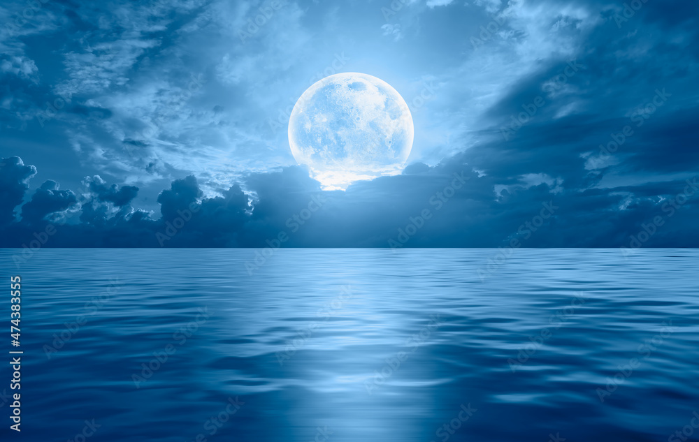 Night sky with full bright moon in the clouds, blue sea in the foreground Night sky with full bright moon in the clouds, blue sea in the foreground