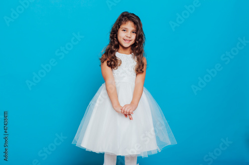 a little curly girl in a white princess dress on a blue background