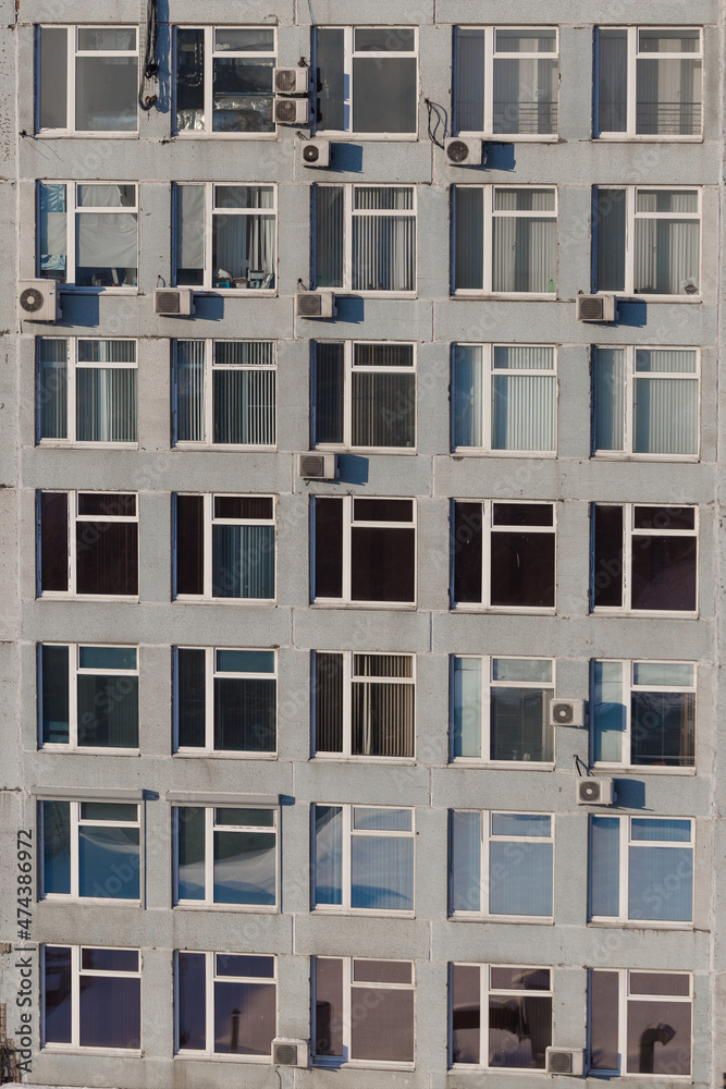 Office building with lots of windows close-up. There are many air conditioners on the facade of the building. Office building with lots of windows close-up. There are many air conditioners on the facade of the building.