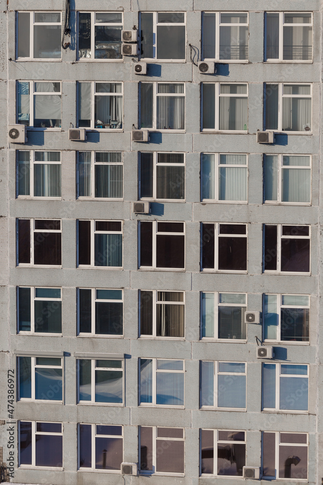 Office building with lots of windows close-up. There are many air conditioners on the facade of the building.