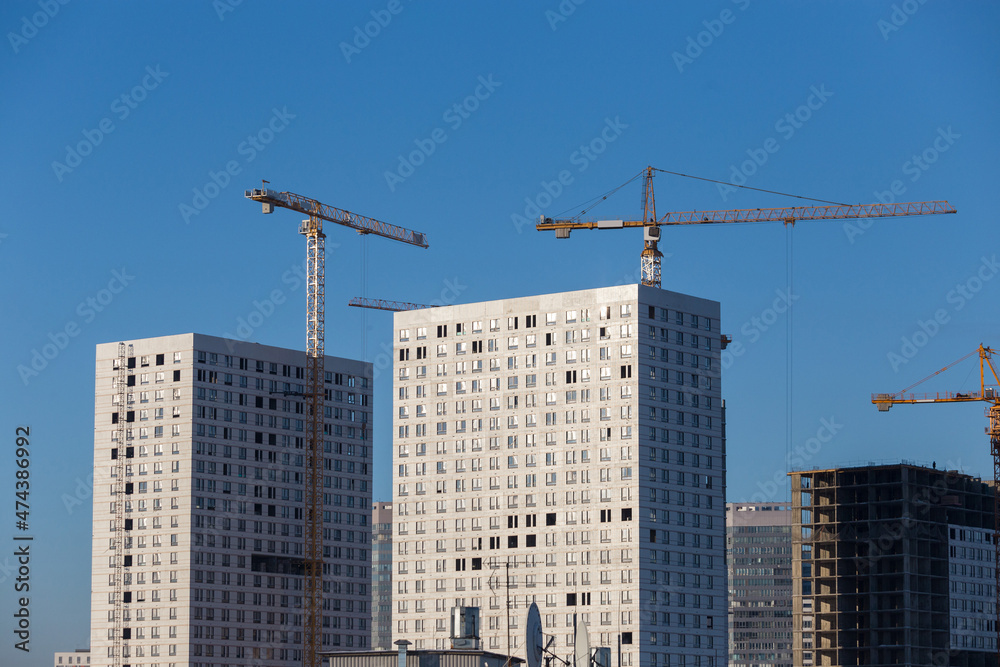 Fototapeta premium Construction of a multi-storey building. A high-rise crane on the construction of a multi-storey building.