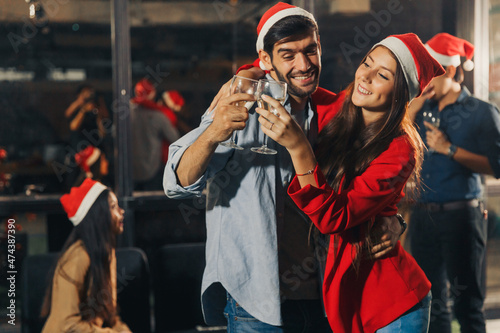 Close up couple having New year party at the modern office together at night. drinking Champagne. Happy diversity people colleague and boss enjoy laughing together in the party. Xmas, new year concept