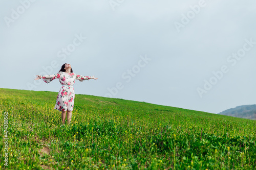 Fototapeta Naklejka Na Ścianę i Meble -  beautiful woman in a spring dress in a blooming garden with green grass