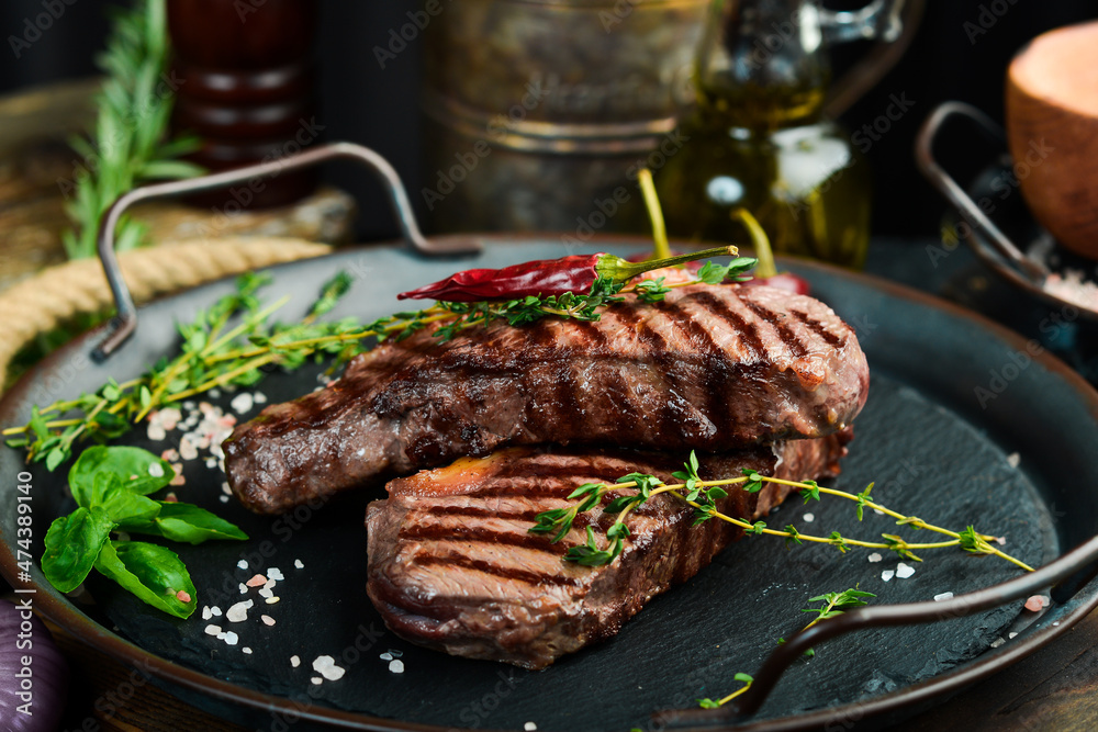 Grilled ribeye beef steak, herbs and spices on a dark table. Top view. Free space for your text. Grilled ribeye beef steak, herbs and spices on a dark table. Top view. Free space for your text.