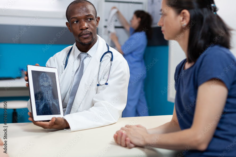 African american pediatrician doctor explaining bones radiography to mother during clinical appointment in hospital office. Radiologit man discussing xray medical expertise. Health care service African american pediatrician doctor explaining bones radiography to mother during clinical appointment in hospital office. Radiologit man discussing xray medical expertise. Health care service