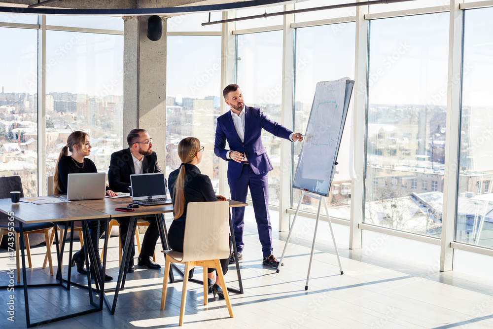 © DSMT - Business people working together in a modern office with cityscape view. The director tells the staff about new technologies. Office work concept