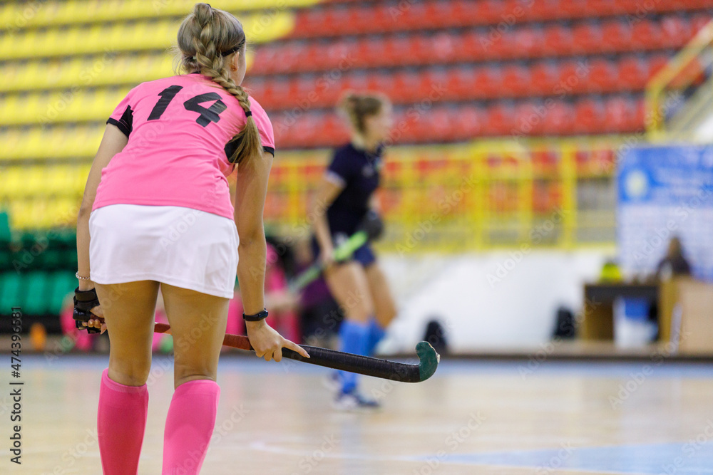 Young girl hockey player playing indoor hockey. Image of female player with stick with copy space