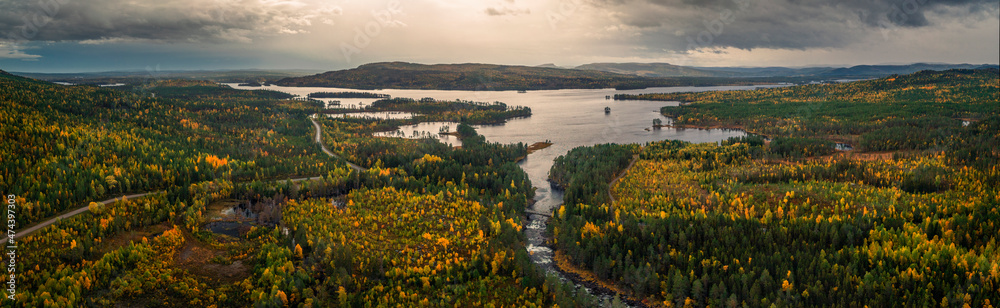 Panorama landscape along Wildernes Road with forest and lake in autumn in Lapland in Sweden from above, colored trees and clouds in sky.