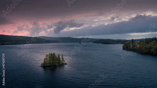 Island with trees in lake on Wilderness Road in Lapland in Northern Sweden  in the sunset from above.